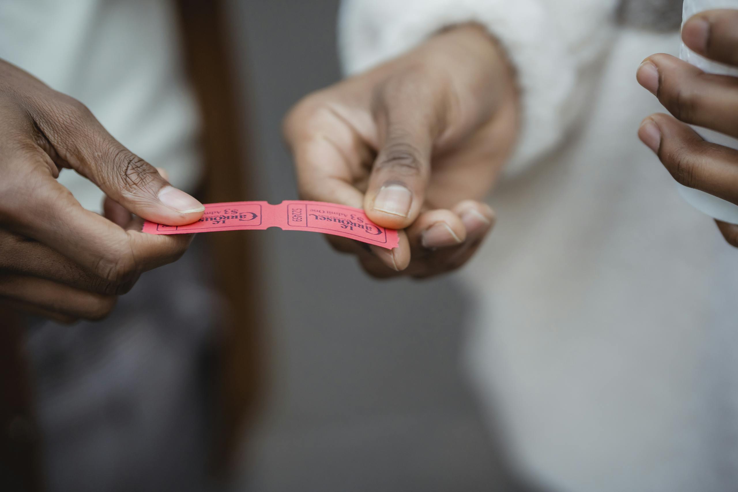 Crop unrecognizable African American friends holding small paper tickets in hands on street in daytime