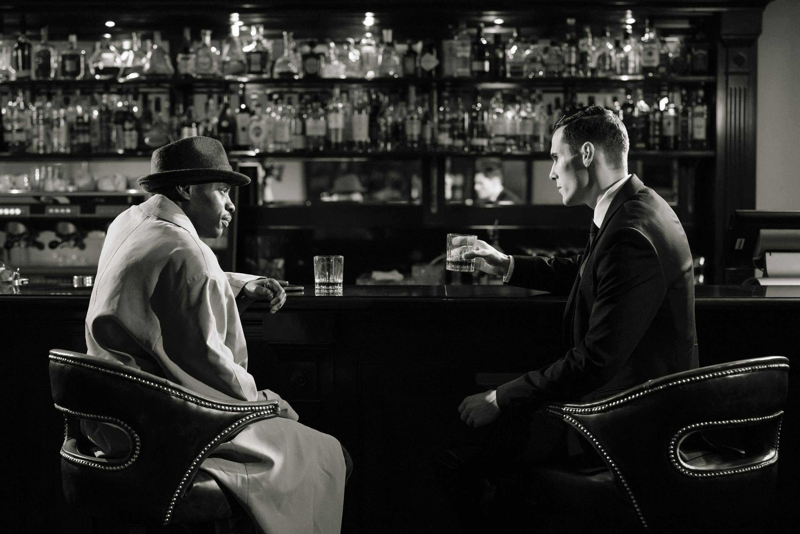 Monochrome Photo of Men Sitting in Front of Bar Counter